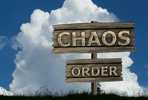 Zwei Holz-Schilder/Wegweiser Chaos und Order, im Hintergrund blauen Himmel mit einer gro&szlig;en Wolke