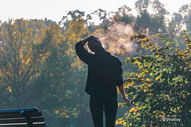 Person im Park macht Nackendehn&uuml;bungen