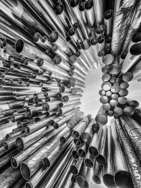 Schwarz-Wei&szlig;-Fotografie von zahlreichen Metallrohren, die dynamisch in den Himmel ragen