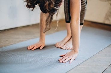 Eine Frau dehnt sich auf einer Sportmatte.