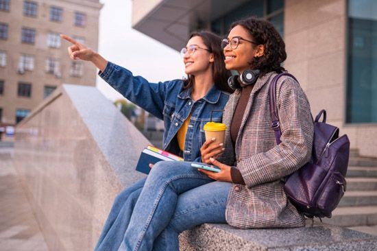 2 junge Frauen auf einer Mauer