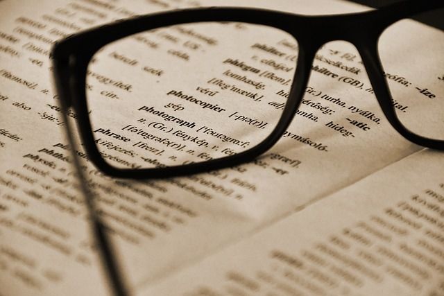 Nahaufnahme einer Brille vergr&ouml;&szlig;ert und auf einer Buchseite abgelegt