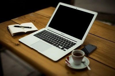 Laptop und Kaffeetasse stehen auf einem Tisch