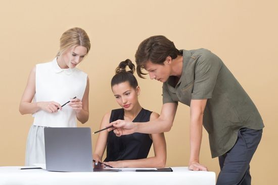 Drei Menschen die sich etwas anschauen auf einem Laptop 