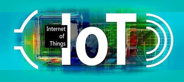 Das Bild zeigt den Schriftzug "IoT" (Internet of Things) vor einem bunten, technologisch gestalteten Hintergrund
