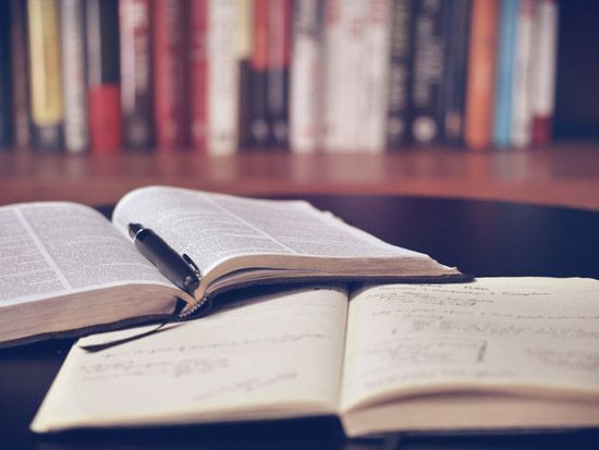 Zwei B&uuml;cher mit Stiften die auf einem Tisch liegen 