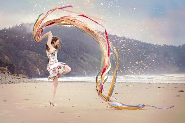 Eine Frau am Strand schwing fr&ouml;hlich bunte B&auml;nder.