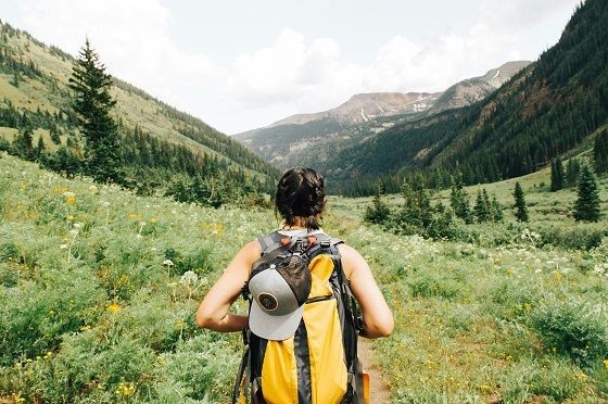 Eine Frau mit Rucksack blickt in ein Bergtal.