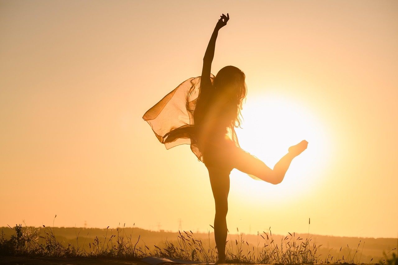 tanzende Frau mit Sonne im Hintergrund