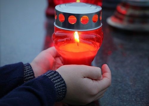H&auml;nde halten ein rotes Grablicht