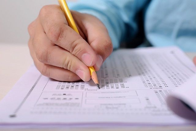 Stift in einer Hand, die ein Pr&uuml;fungsformular ausf&uuml;llt