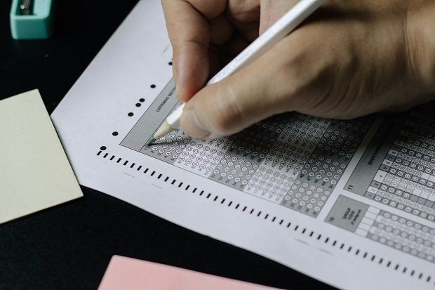 Hand mit Stift, die einen Pr&uuml;fungsantwortbogen ausf&uuml;llt
