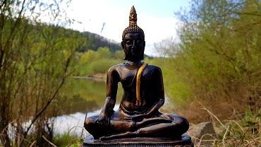 Sitzende Skulptur vor einem Teich