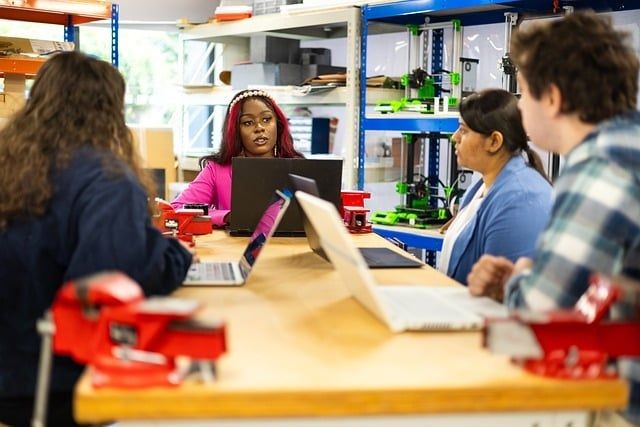 4 Menschen mit aufgeklappten Laptops beim Lernen