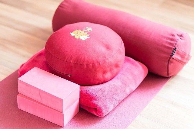 Yoga Equipment auf der Matte am Boden angereiht - Yogakissen, Yogabl&ouml;cke, Yogabolster