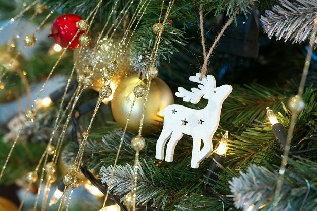 Ein wei&szlig;er Holz-Rentier-Anh&auml;nger h&auml;ngt an einem beleuchteten Weihnachtsbaum