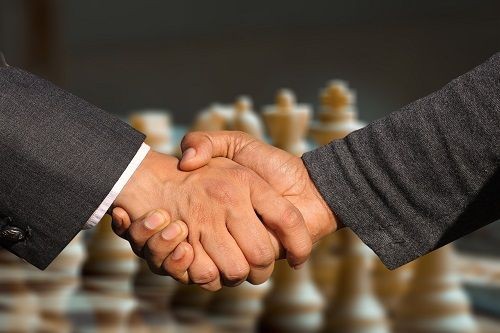 Handshake, im Hintergrund ein Schachspiel