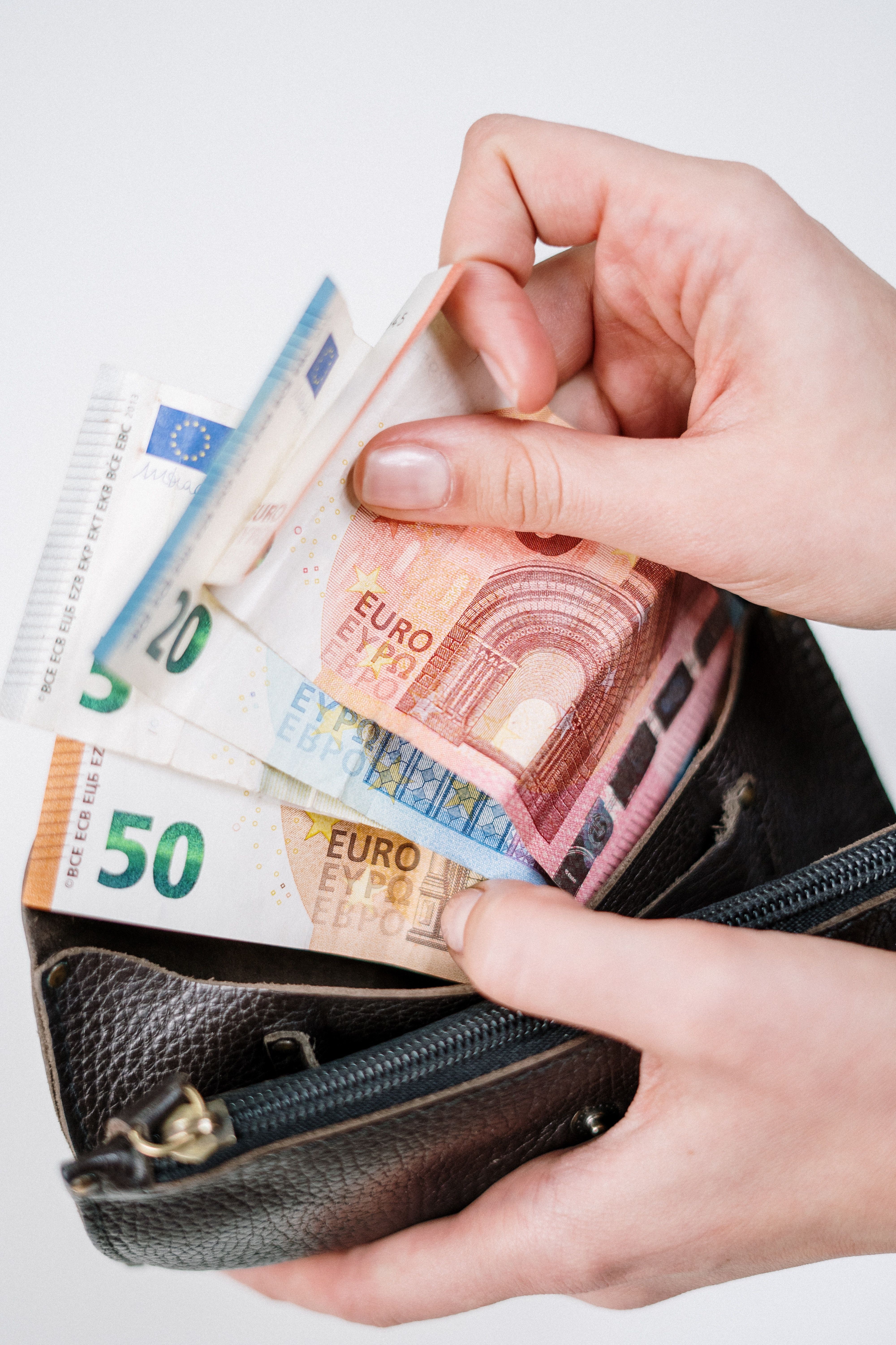 Hand, die Euro-Banknoten aus einer schwarzen Geldb&ouml;rse entnimmt