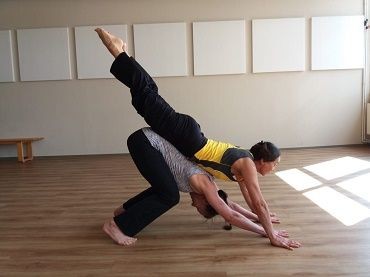 zwei Personen f&uuml;hren eine Yoga-&Uuml;bung mit hands on durch