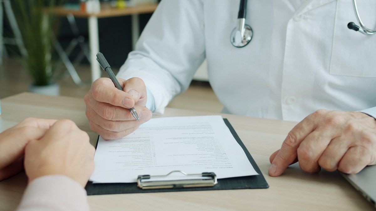 Patient und Arzt sitzen am Tisch mit einer Checkliste 