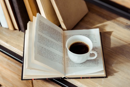 Foto Nahaufnahme einer Tasse Kaffee und eines Buches auf einem Holztisch